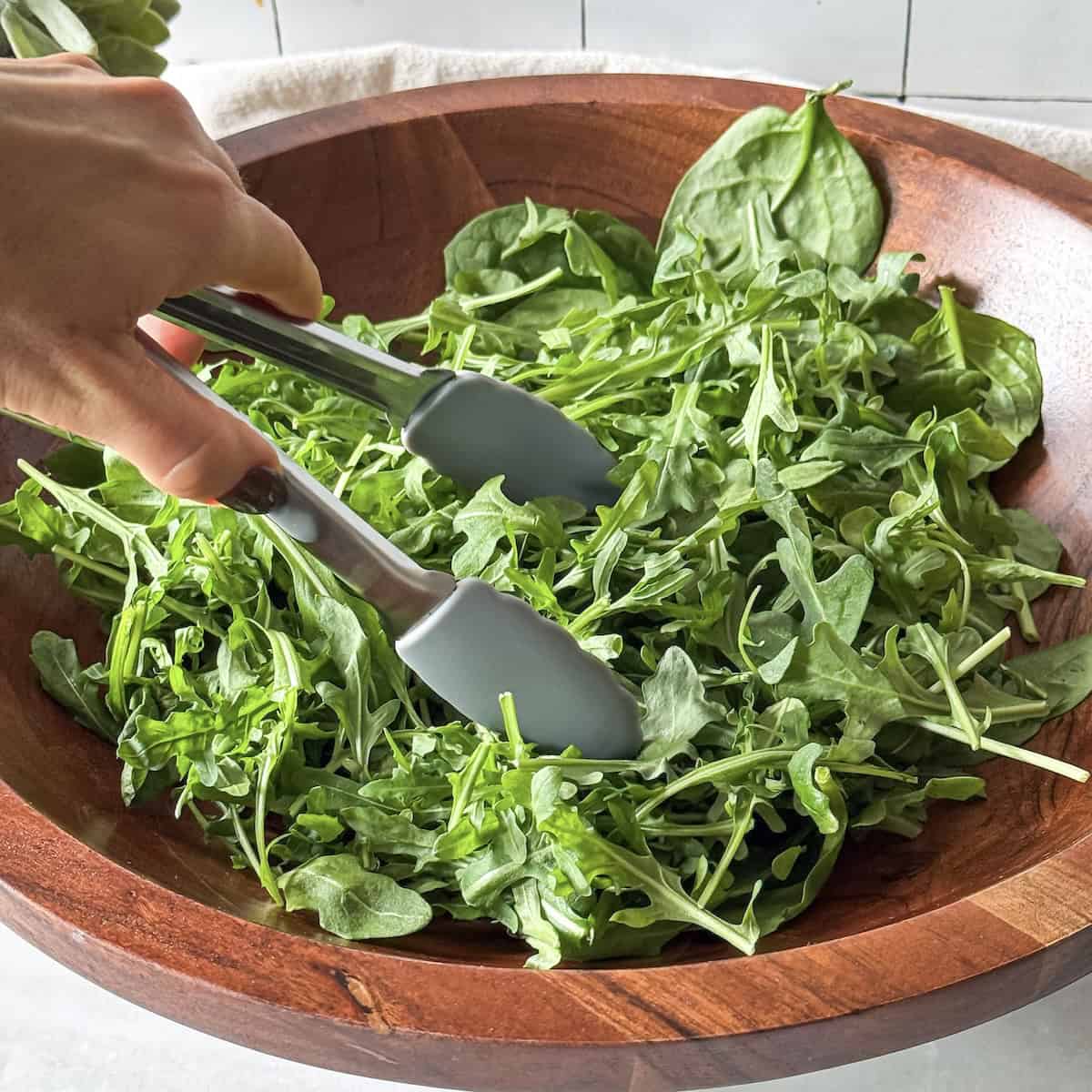 human hand combining spinach and arugula.