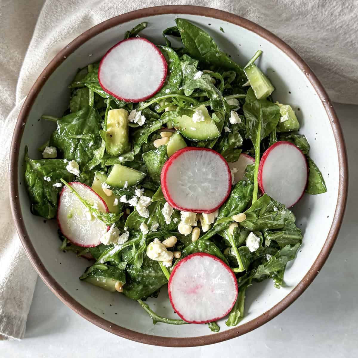 overhead view of spinach and arugula salad in a bowl.