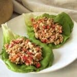 side view of 2 thai chicken lettuce wraps on a plate.