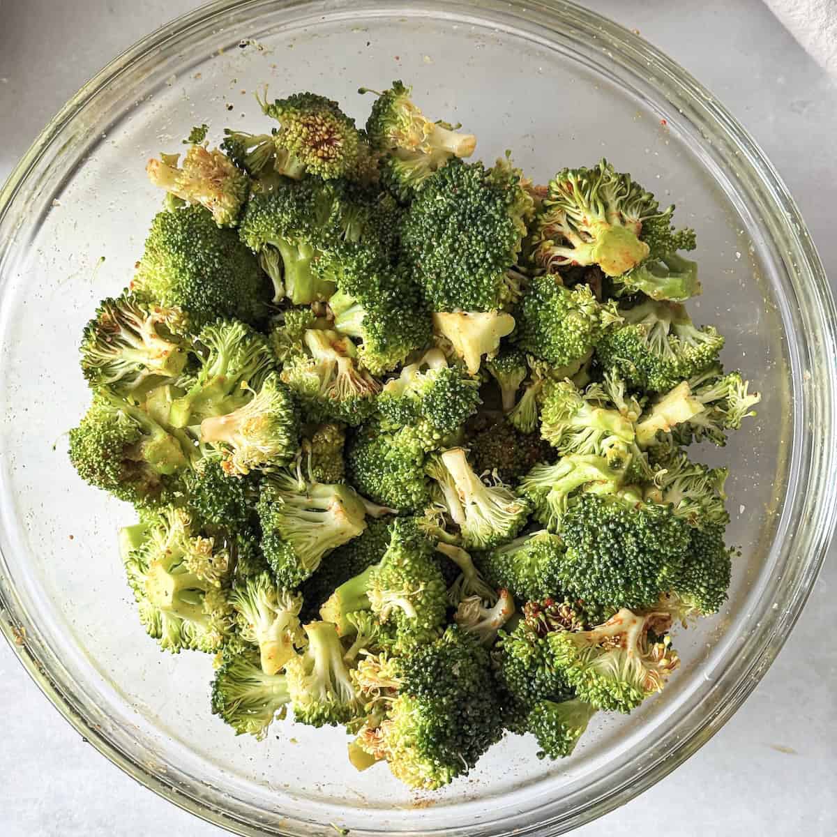 broccoli in a glass bowl tossed in olive oil.