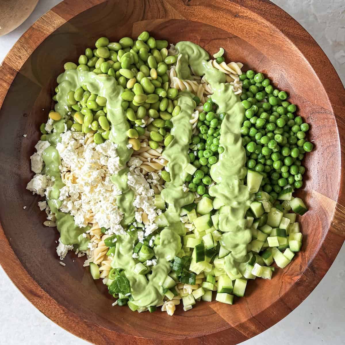 overhead view of green goddess pasta salad with dressing added.