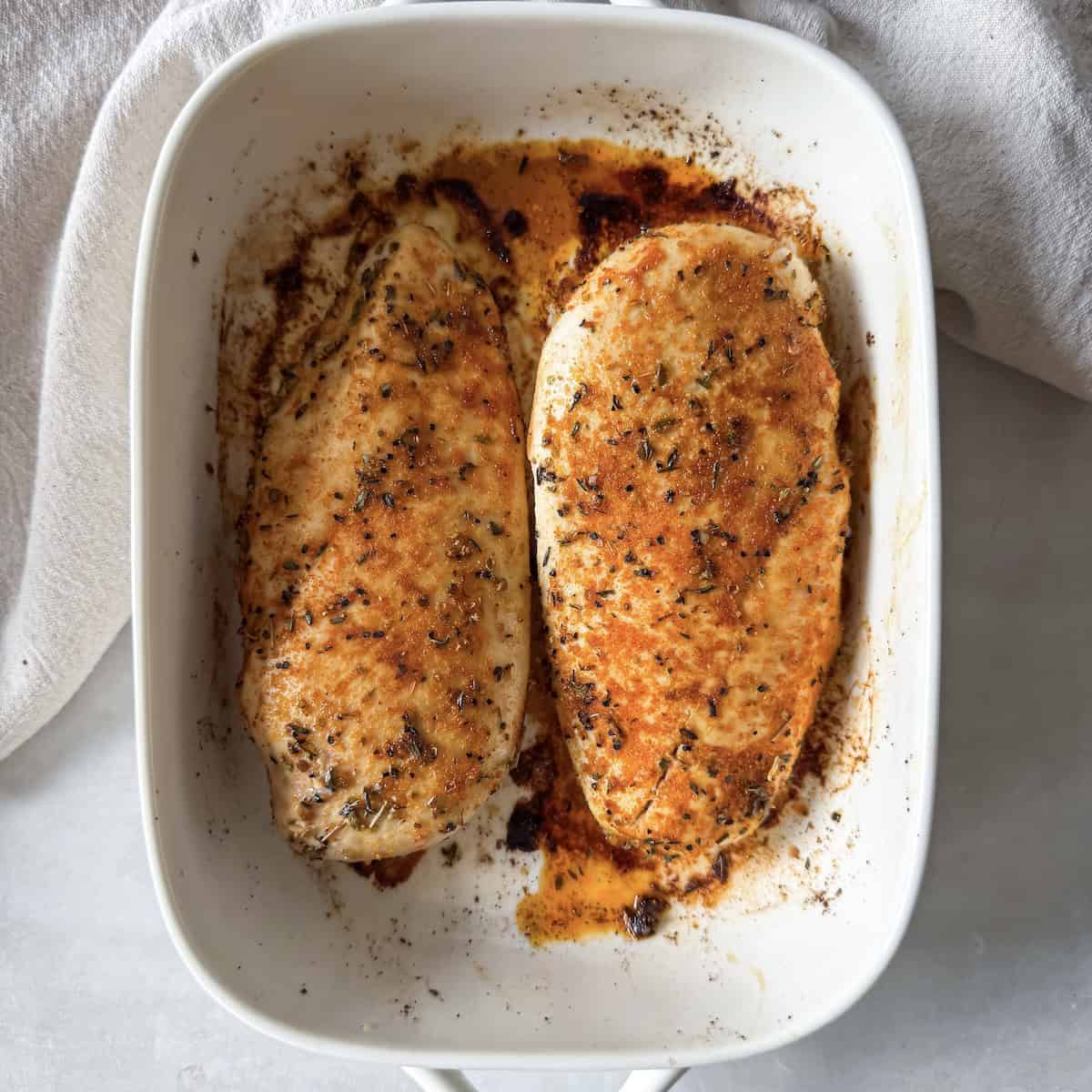 oven baked chicken breast in a baking dish overhead view.