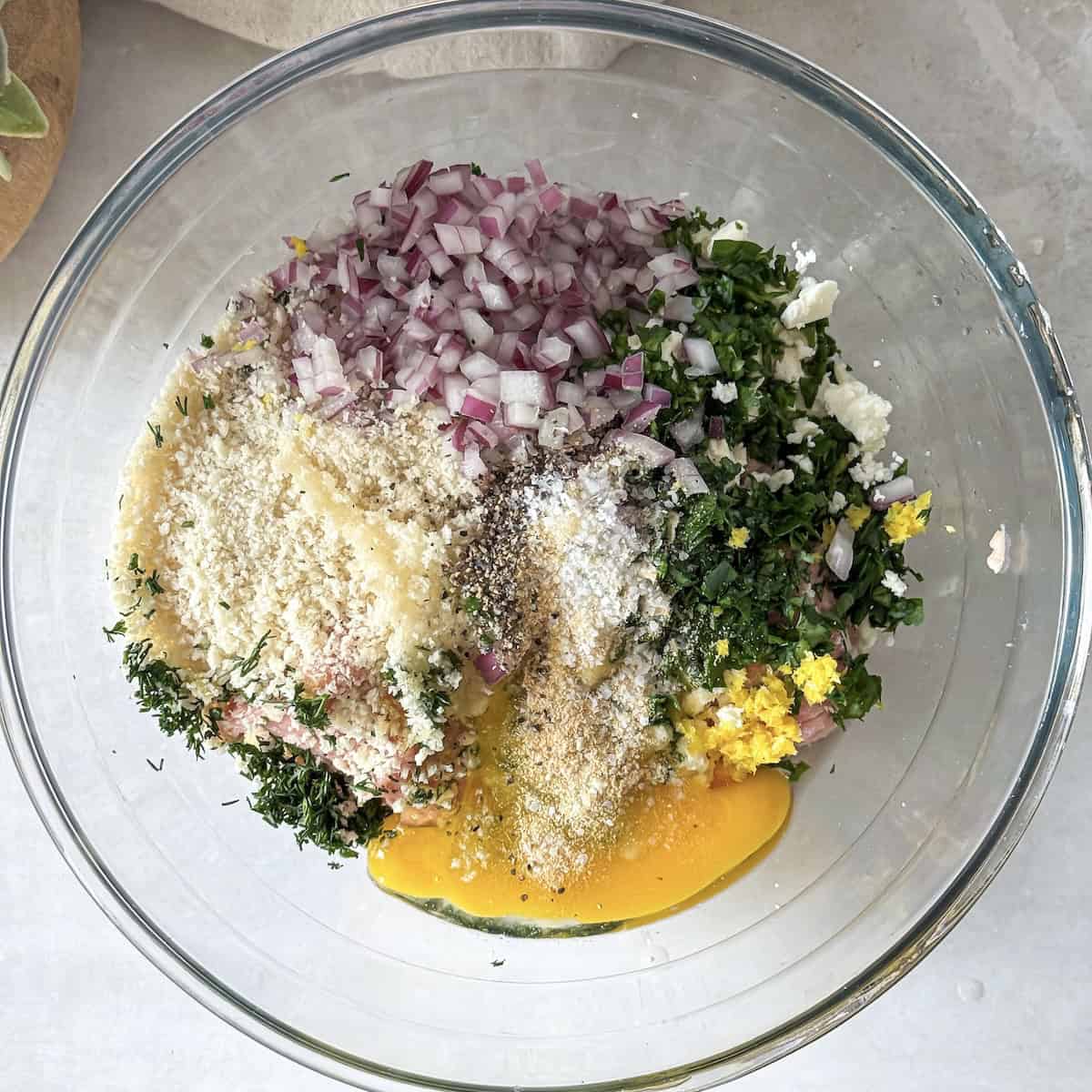overhead view of turkey meatball ingredients in a glass bowl about to be mixed.