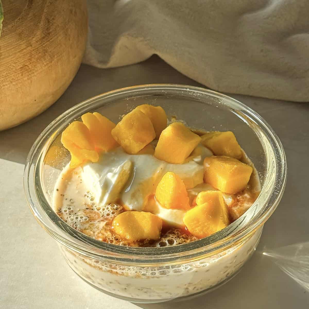 mango overnight oats being made in a glass container.