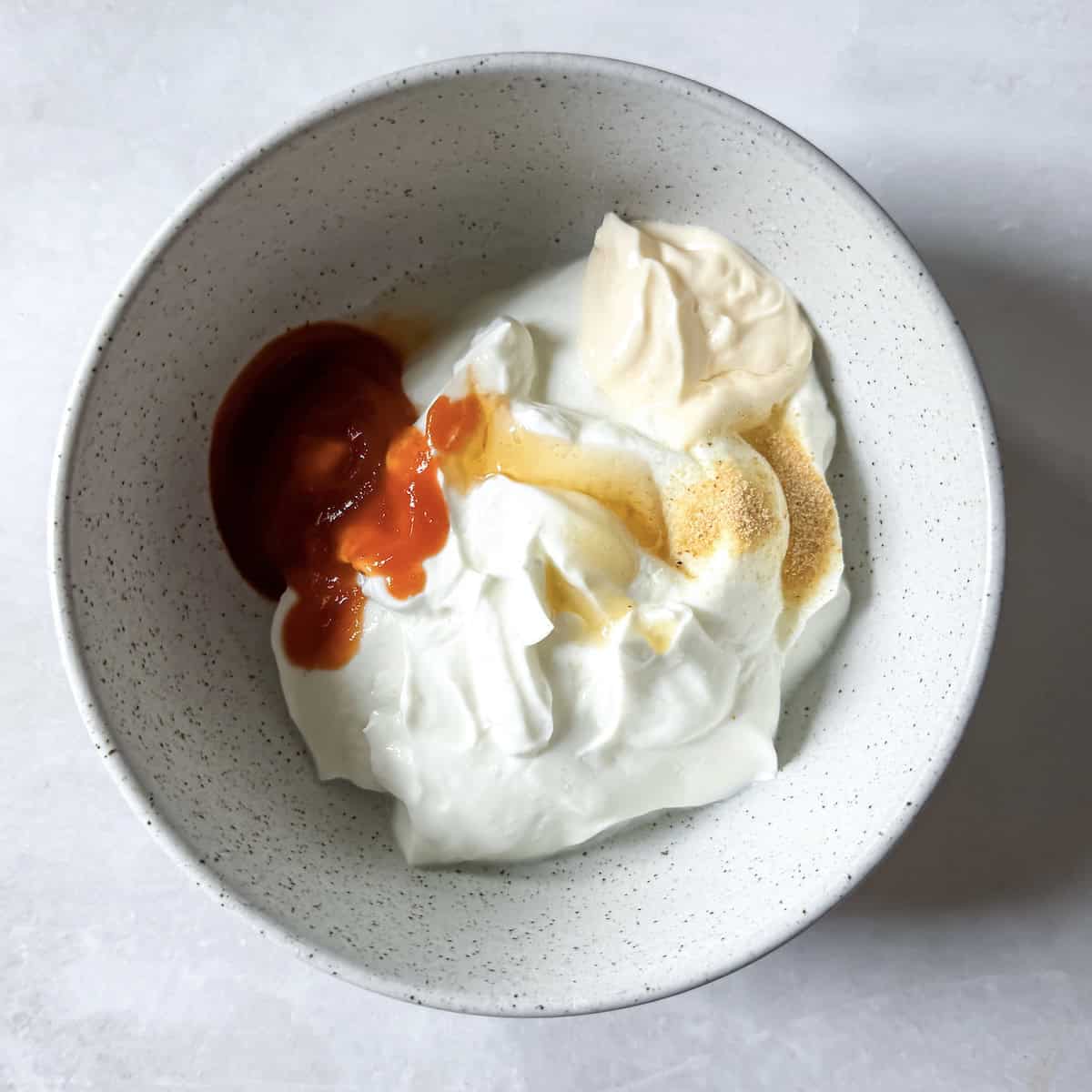 greek yogurt sriracha sauce ingredients in a bowl..