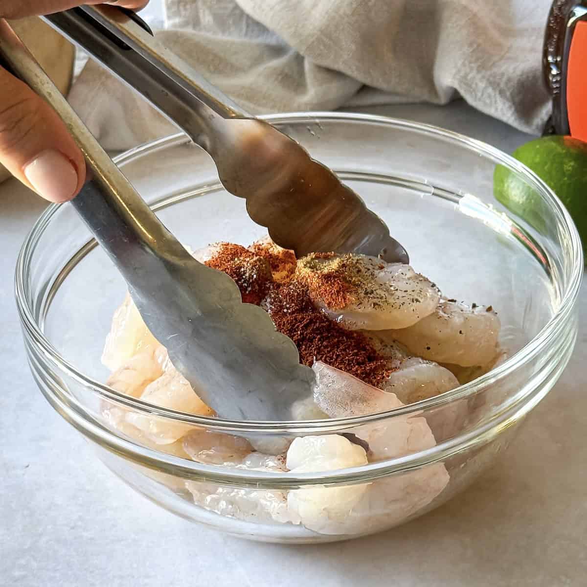chili lime shrimp in a bowl being tossed in seasonings.