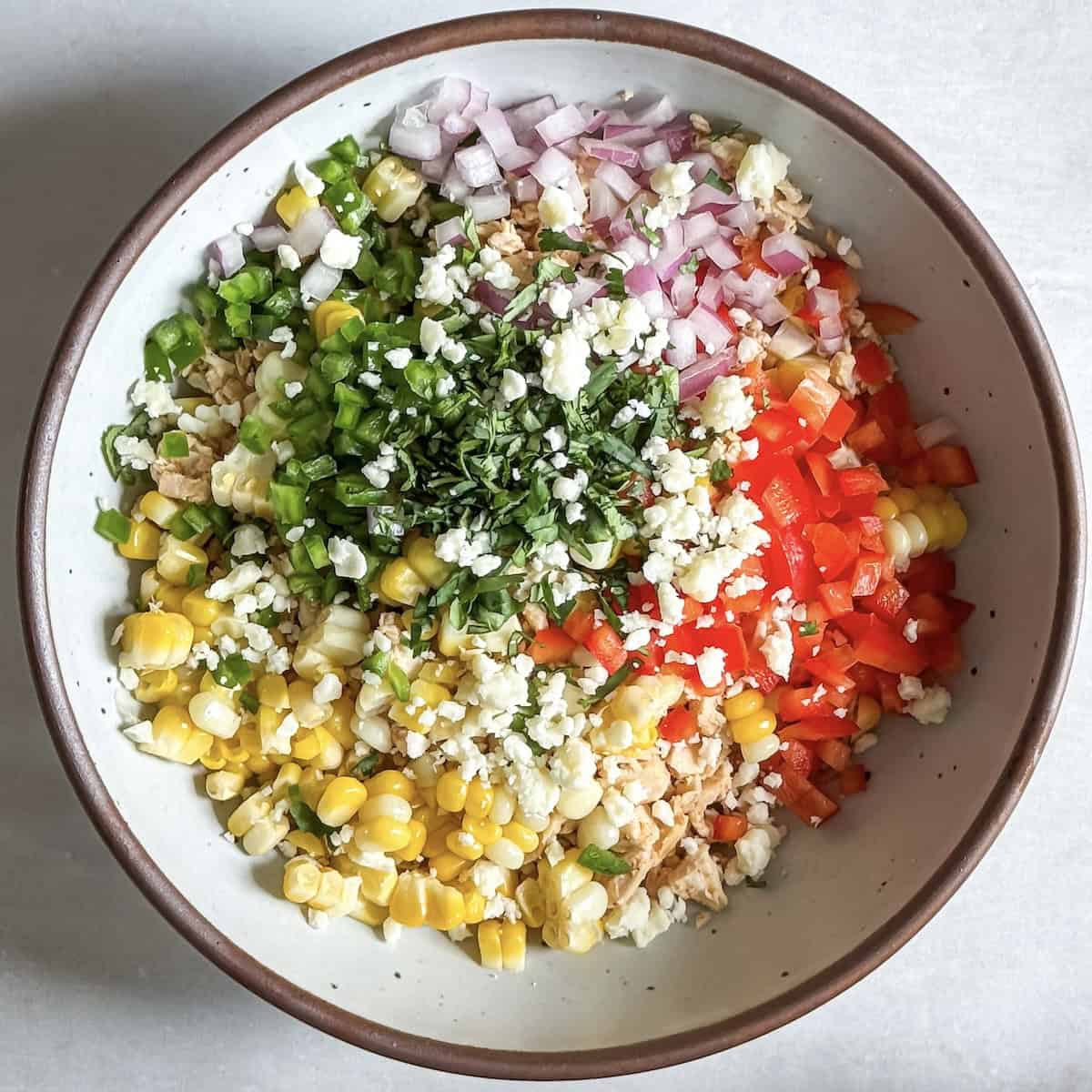 overhead view of street corn chicken salad ingreidnets in a bowl.