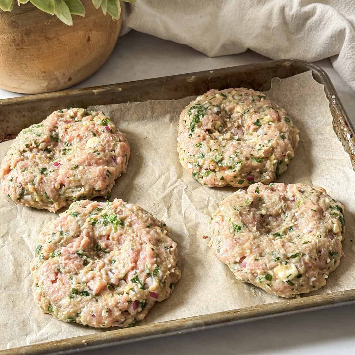 turkey burger feta spinach formed into 4 patties on a baking sheet.