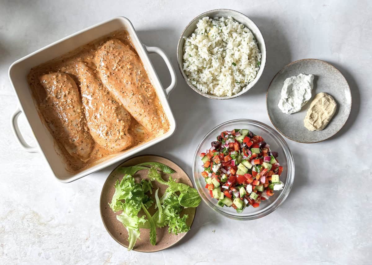 greek chicken and rice bowl ingredients on a table.