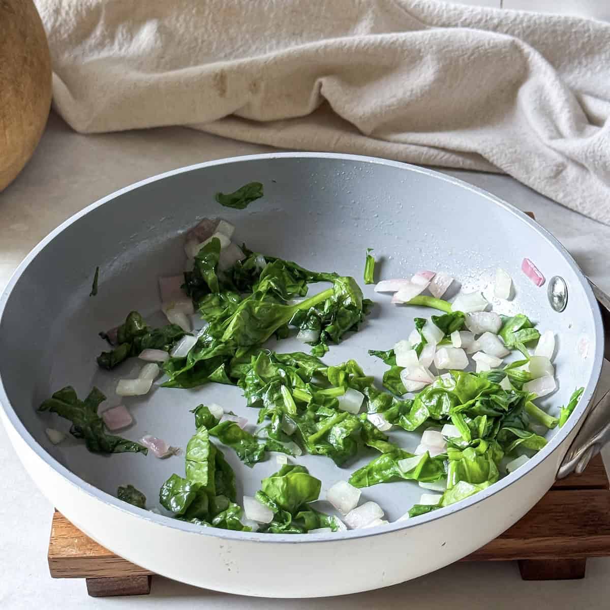 red onion and spinach sauteed in a pan.