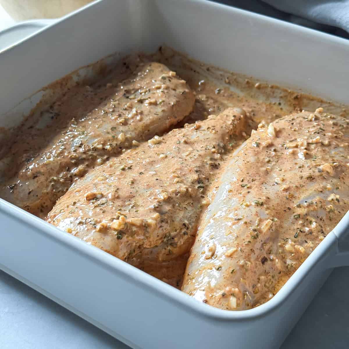 side view of greek yogurt chicken marinade on chicken in a pan.