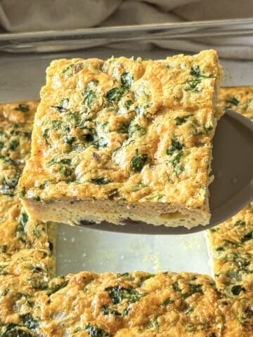 Slice of Southwest egg casserole with green peppers and cheese on a spatula.
