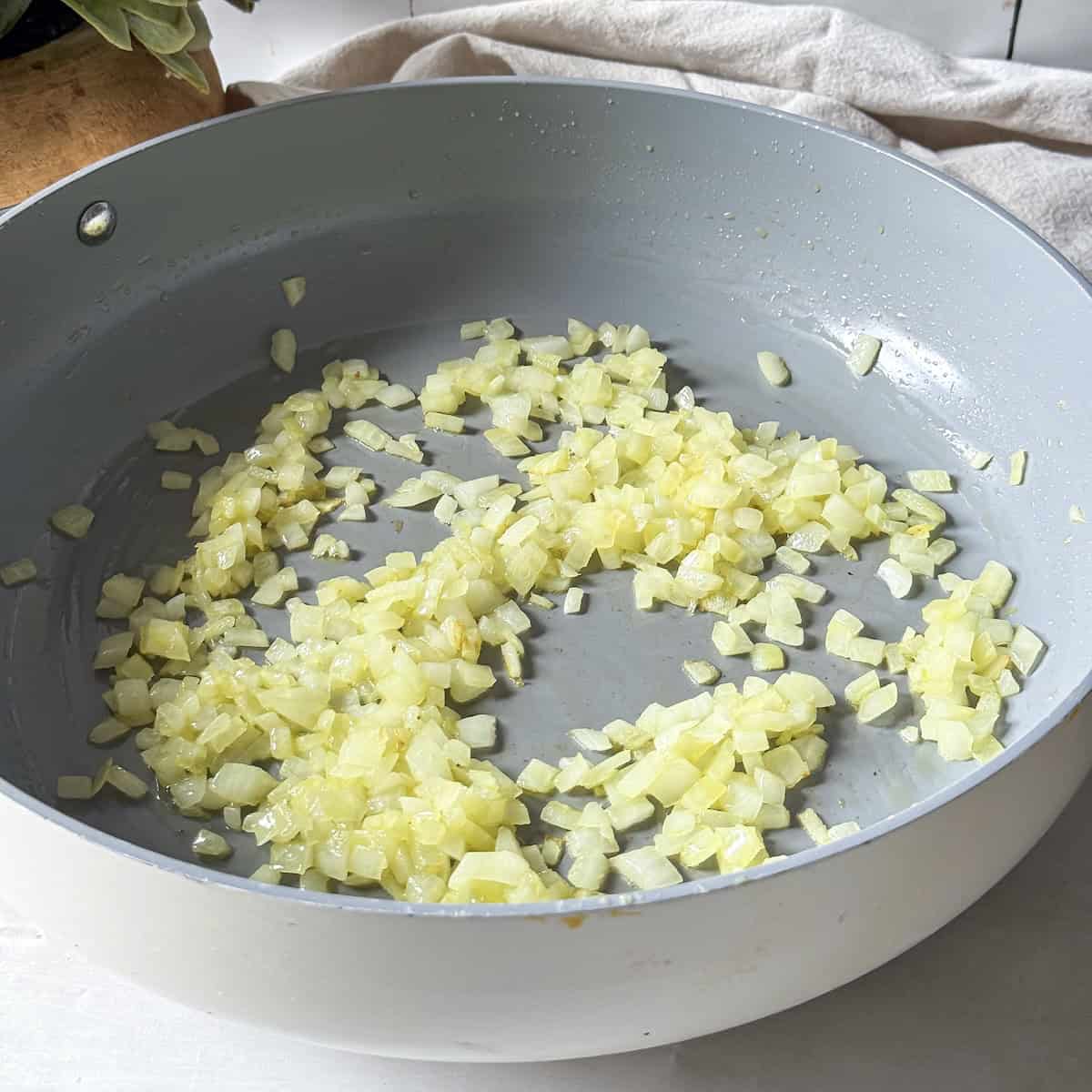 sauteed diced onions in a gray colored non-stick skillet.