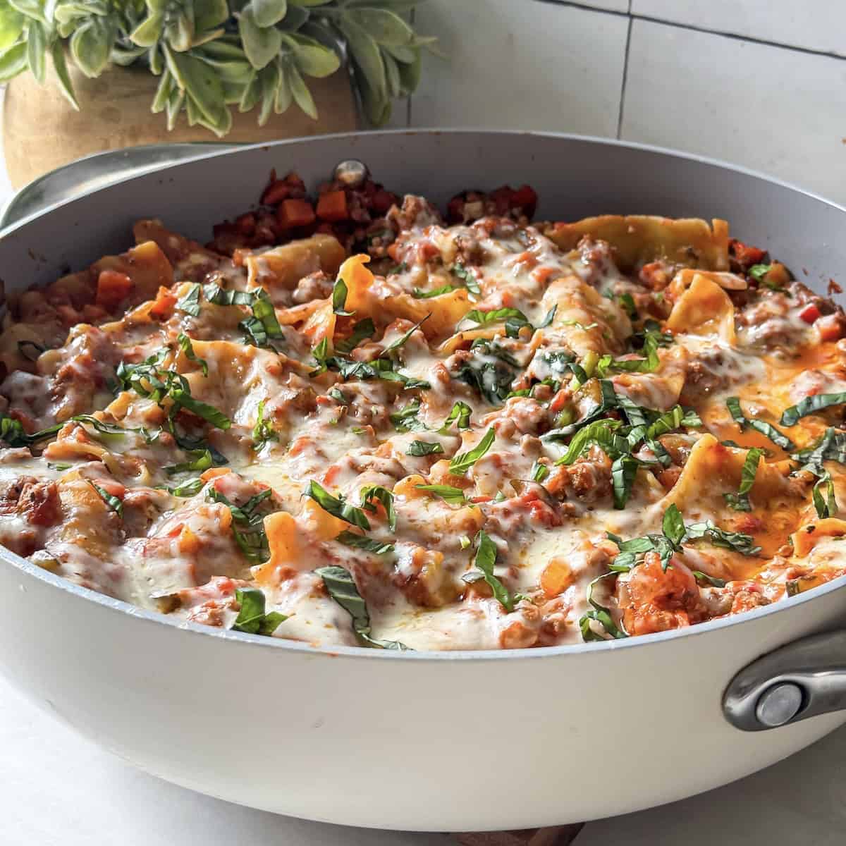 cooked lasagna noodles, ground beef, vegetables, and melted cheese on top