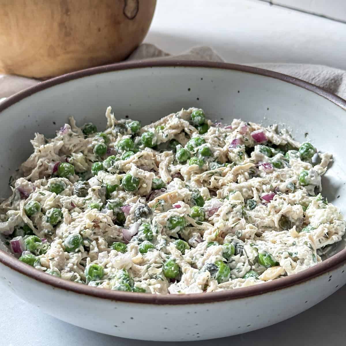 A bowl of chicken salad with green peas right after it was made and mixed together.
