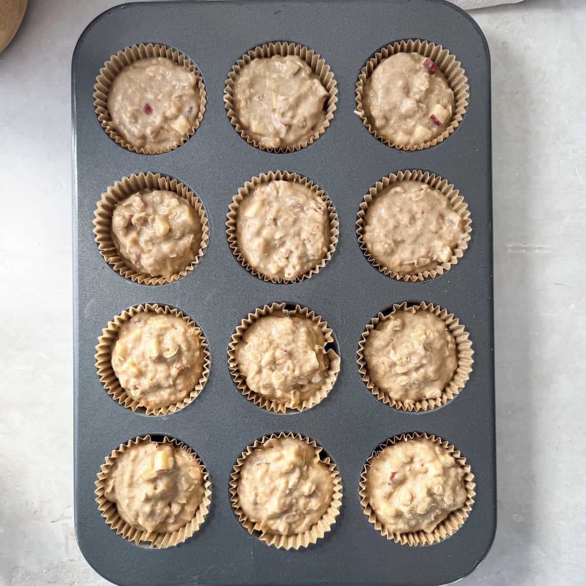 Apple oat muffin batter in a 12 cup muffin tin right before doing into the oven.