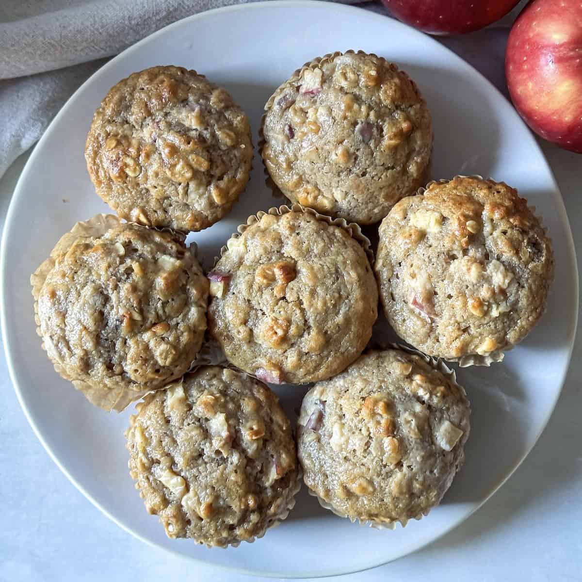 A plate of apple cinnamon aot muffins on a plate right after coming out of the oven.