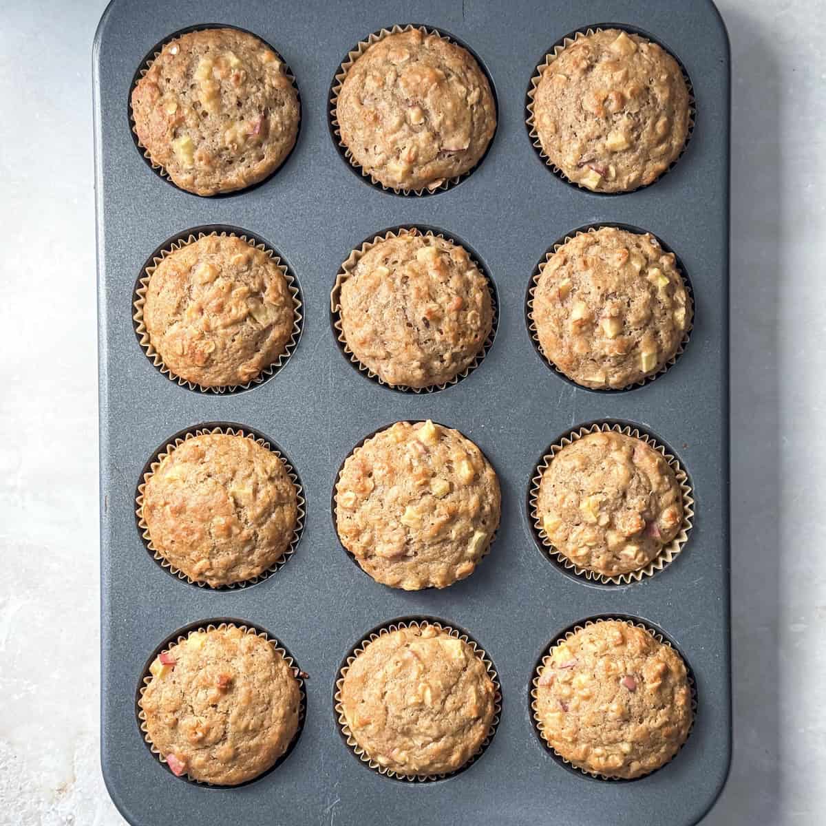 apple oat muffins in a muffin pan right after being baked.