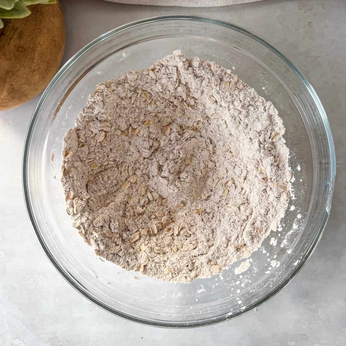 Dry ingredients for apple oat muffins in a glass mixing bowl just after being combined.