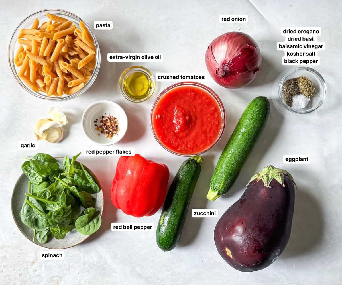 ingredients for roasted vegetable pasta in separate containers on a table labeled.