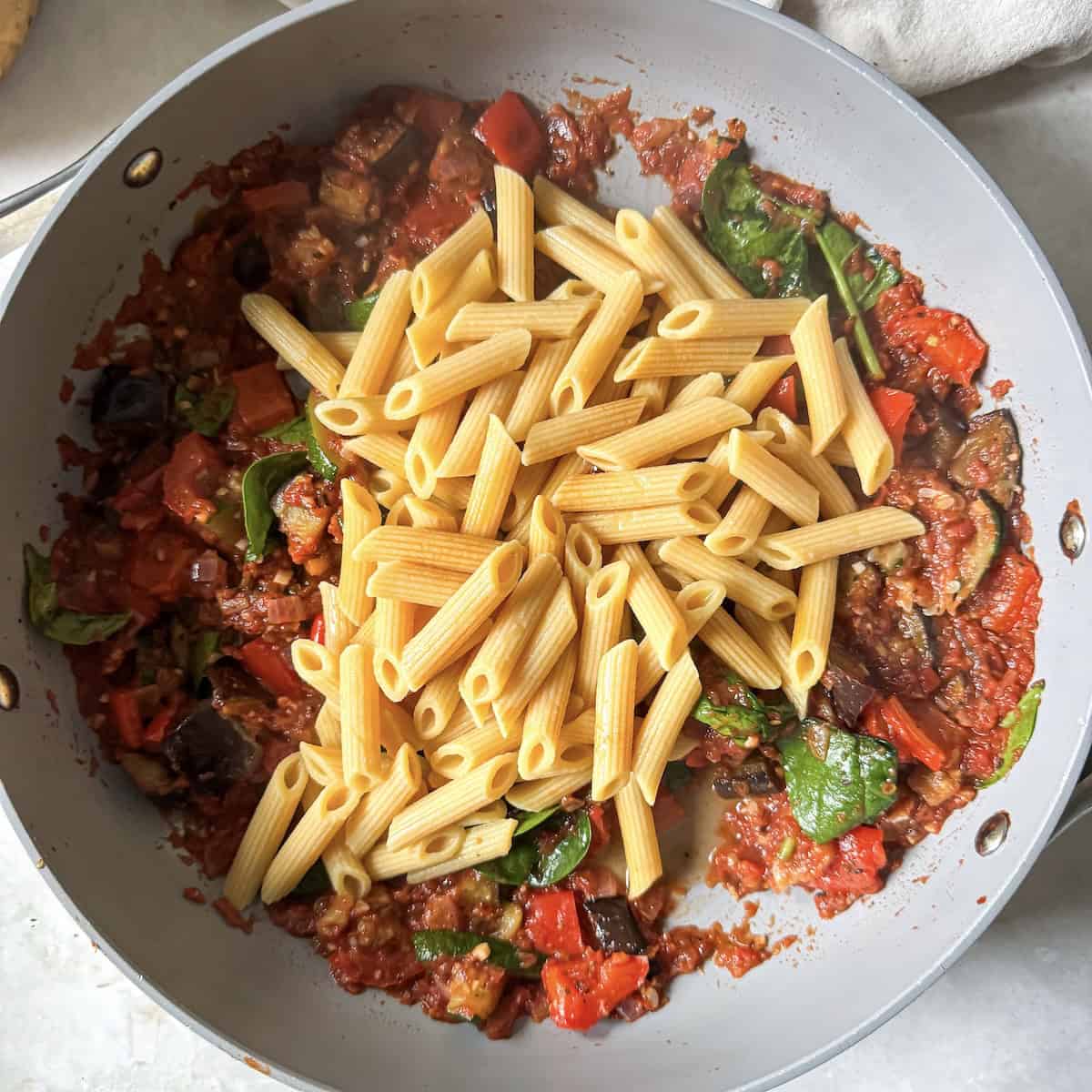 pasta added to tomato sauce and roasted vegetables.