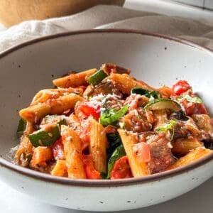 roasted vegetable pasta in a bowl with freshly shredded parmesan on top.