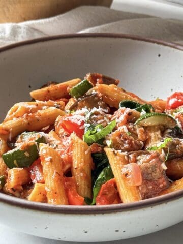 roasted vegetable pasta in a bowl with freshly shredded parmesan on top.