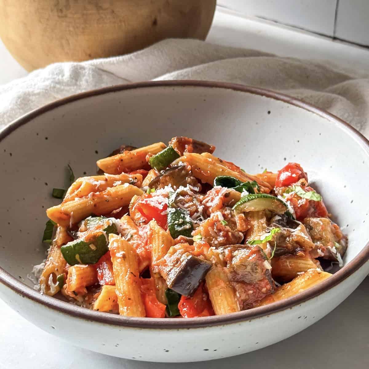 roasted vegetable pasta in a bowl with freshly shredded parmesan on top.