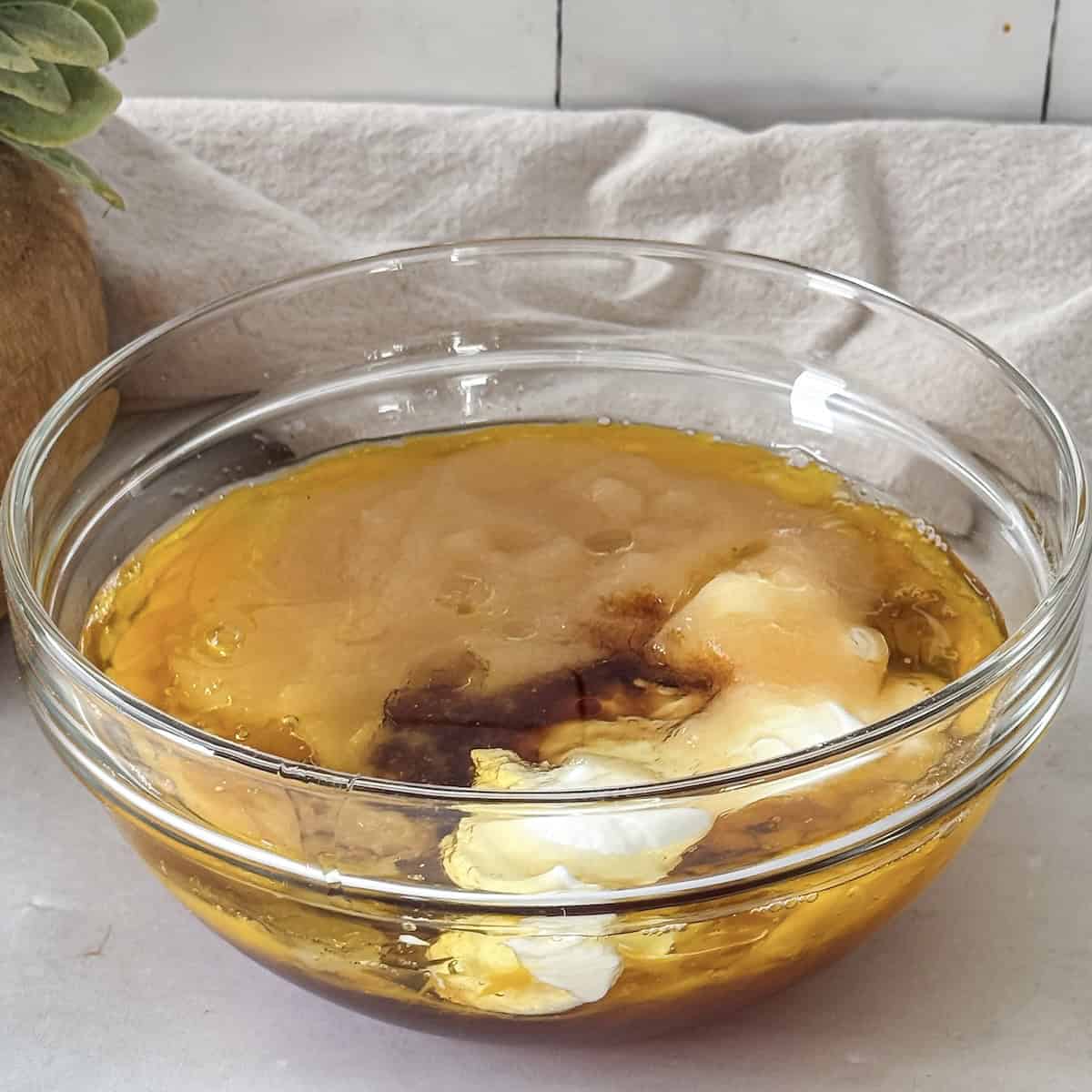 Wet ingredients for apple oat muffins in a glass bowl right before being mixed.